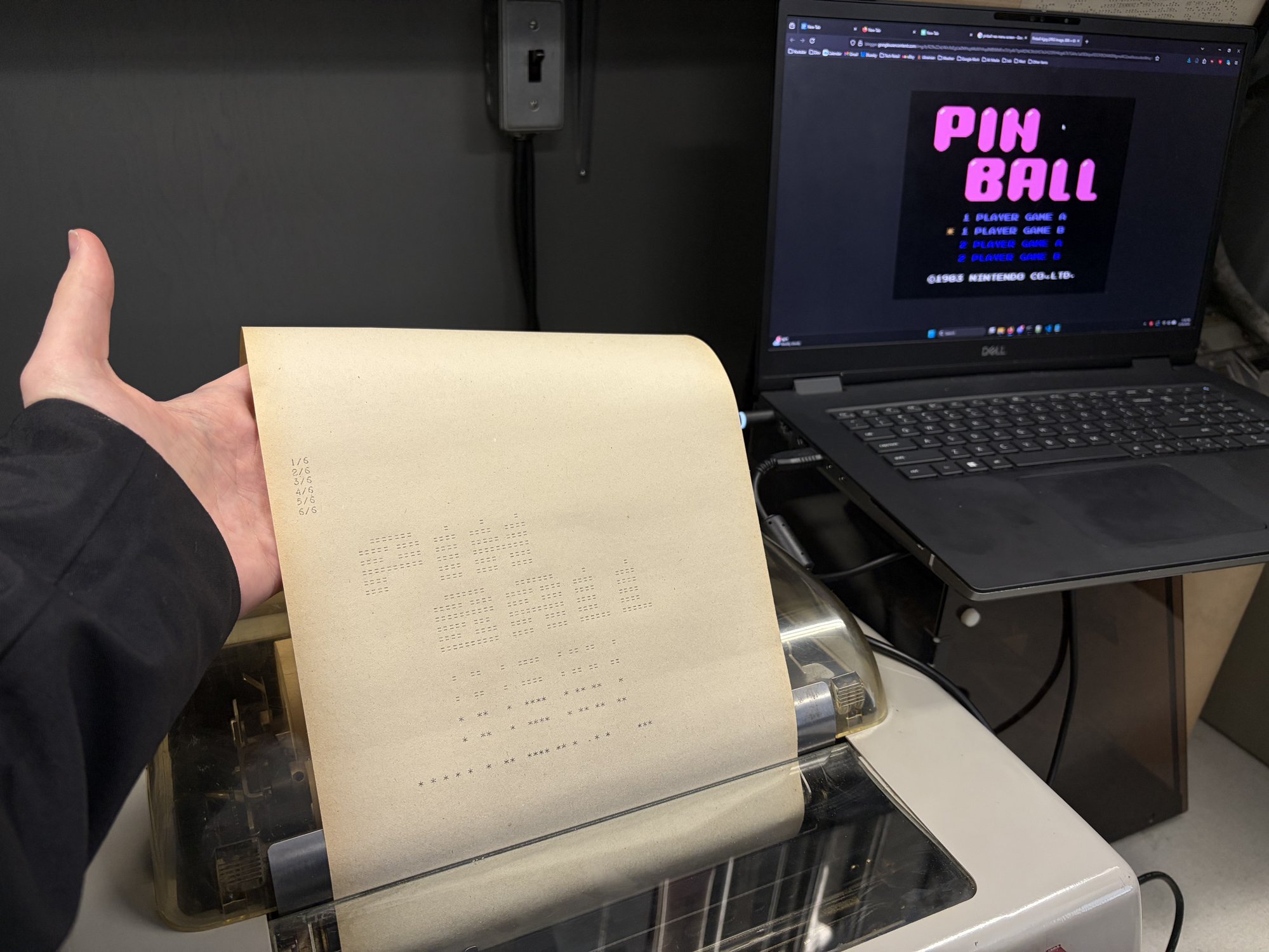 A teletype printout of an NES Pinball frame held next to a laptop showing the same frame.
