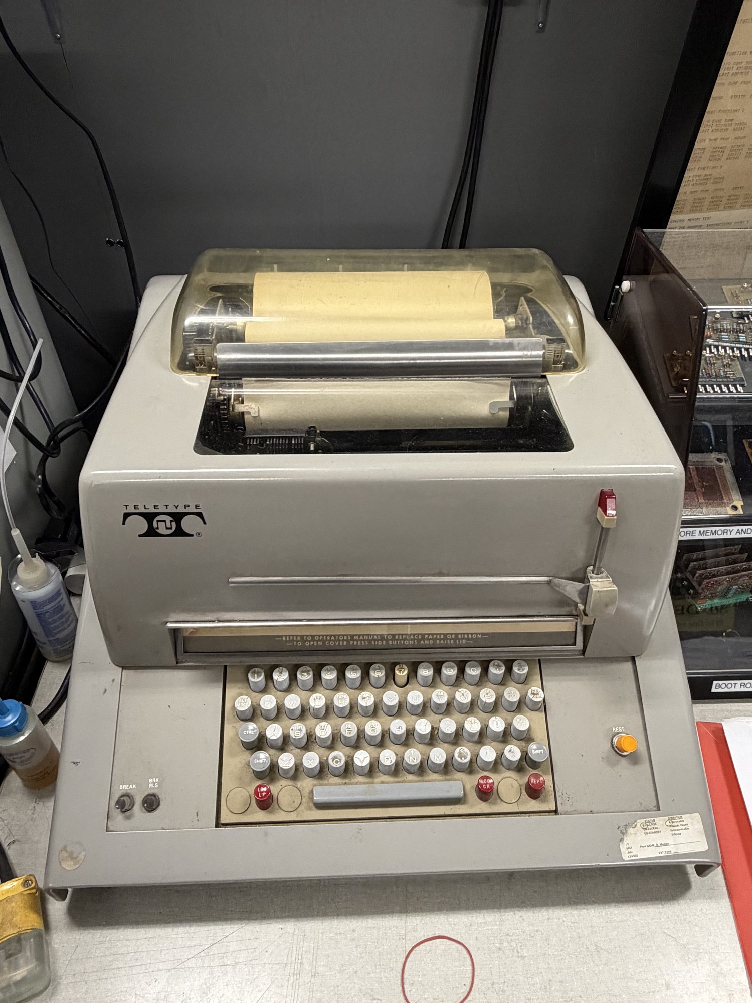 A Model 35 Teletype with its dust cover, paper spool, and keyboard.
