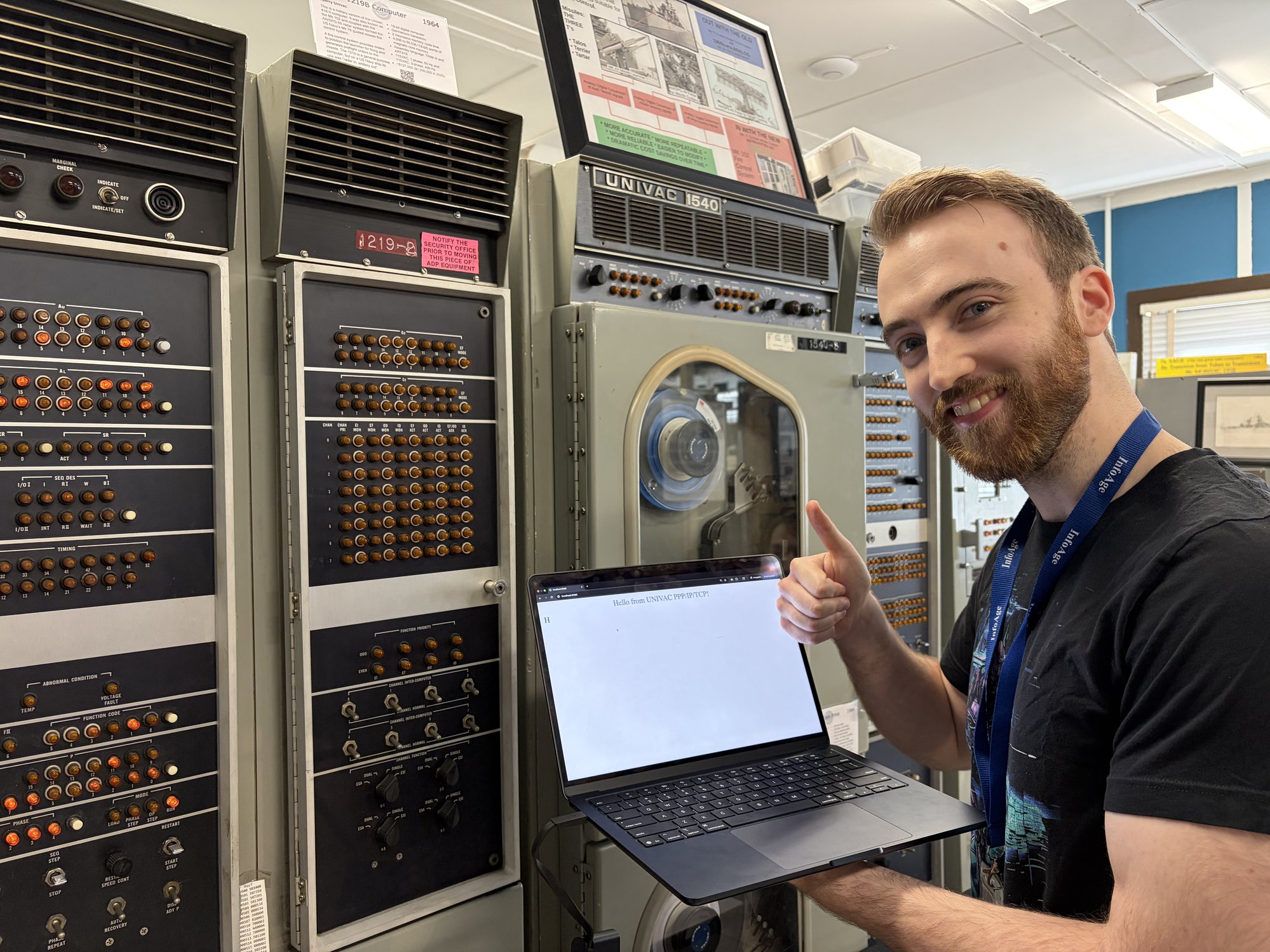 Nathan giving a thumbs up next to the UNIVAC while holding a laptop with a webpage open.